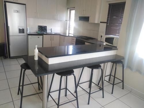 a kitchen with a black counter top and stools at Posh 2 in Durban