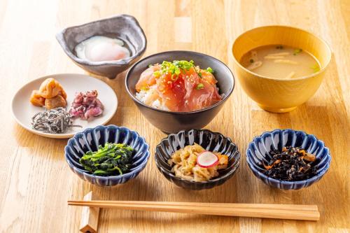 Tokyu Stay Takanawa Shinagawa Area في طوكيو: مجموعة من أطباق الطعام والعواد على طاولة