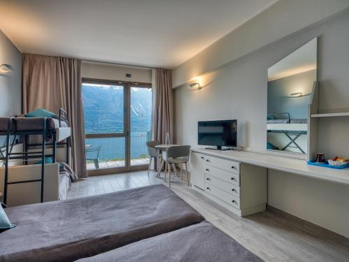 a bedroom with a bed and a desk with a television at Hotel San Pietro in Limone sul Garda