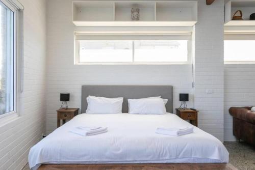1 dormitorio con 1 cama blanca grande y 2 mesitas de noche en CLIFFSIDE: BONDI BEACH, en Sídney