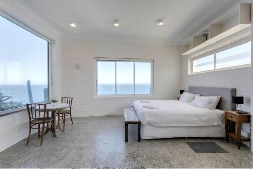 a bedroom with a bed and a table and chairs at CLIFFSIDE: BONDI BEACH in Sydney
