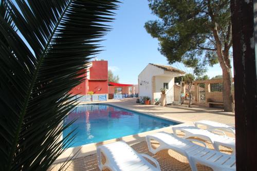 a swimming pool with white chairs and a palm tree at Casa La Noria by Rental Olé in Murcia