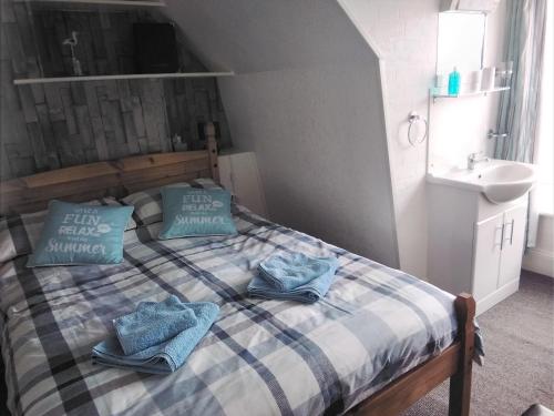 een slaapkamer met een bed met blauwe kussens en een wastafel bij Merriedale Guest House in Paignton
