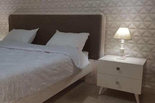 a bed with a night stand with a lamp on it at Cosy and Charming Apartment close to TUNISIA MALL Lac2 Tunis in Tunis