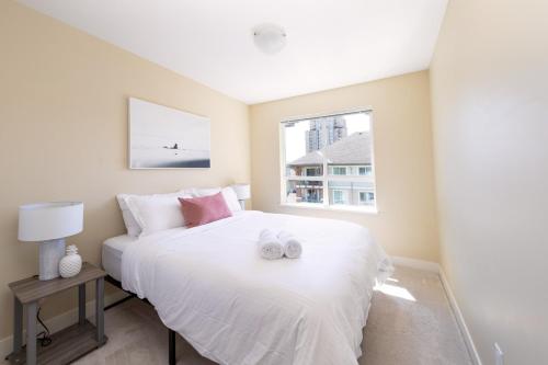 a bedroom with a white bed and a window at Downtown Osprey Condo at Waterscapes in Kelowna
