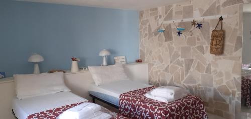 1 dormitorio con 2 camas y pared de piedra en san lorenzo a 4 mt dal mare colore smeraldo a due passi da Marzamemi, en Reitani