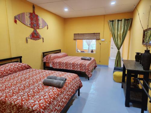 um quarto com 2 camas e paredes amarelas em Gecko Guesthouse em Pantai Cenang