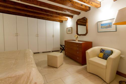 een slaapkamer met een bed, een stoel en een dressoir bij Art Dreams Apartment Dimora Casanova in Venetië