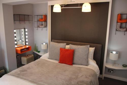 1 dormitorio con 1 cama grande con almohadas de color naranja y gris en The Light Room at no.7 en Hull