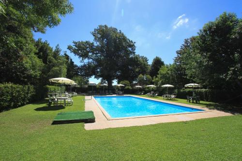 uma piscina num quintal com cadeiras e guarda-sóis em Casa vacanze Il Parco em Manziana