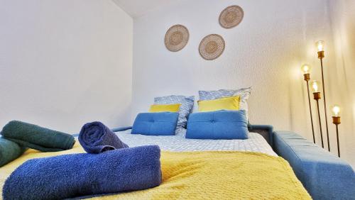 łóżko z niebiesko-żółtymi kocami i poduszkami w obiekcie Le SMART - Parking - Terrasse - Wifi - Mulhouse - Relax BNB w mieście Pfastatt