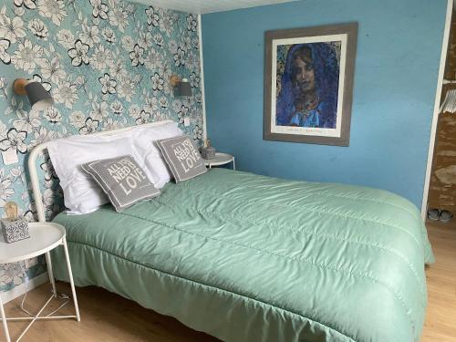 a bedroom with a green bed with a painting on the wall at Les Hauts Complex in Coulaures