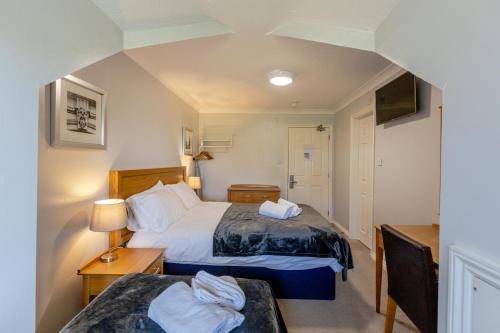 a small room with two beds and a tv at The Angel Hotel in Alton