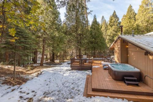 bañera de hidromasaje en una terraza de madera en la nieve en Red Rock Falls Cabin, 8 miles from Yosemite South Gate, with trailhead, Game Room and HotTub, en Oakhurst