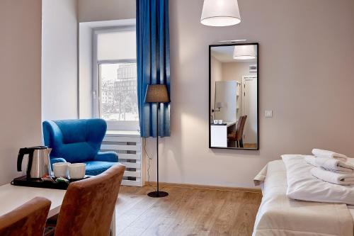 a bedroom with a blue chair and a mirror at Hotel Traffic Poznań Stare Miasto in Poznań