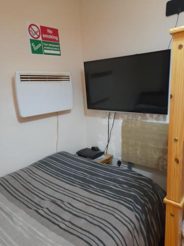 Schlafzimmer mit einem Bett und einem Flachbild-TV in der Unterkunft Bubblesbnb, 1 bedroom flat in London