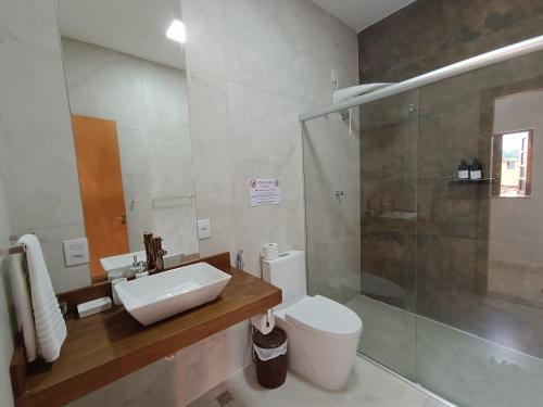 a bathroom with a sink and a toilet and a shower at Pousada Quintal da Lua in Capitólio