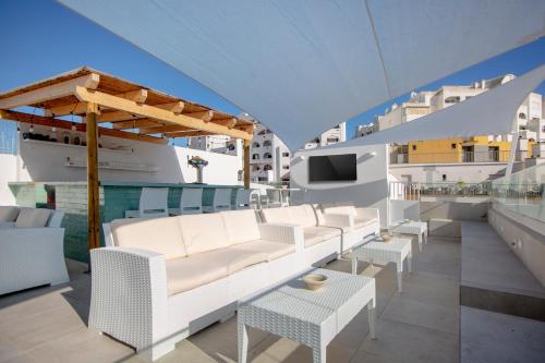 a rooftop deck with white furniture and a tv at Sun Lovers Hostel in Albufeira