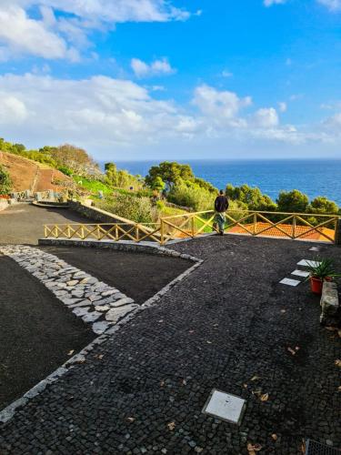 un hombre caminando sobre un puente con vistas al océano en Quinta do Caminho da Igreja TER-Casas de Campo en Velas