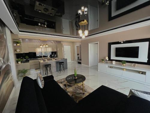 CSO Luxury Residence في مامايا: غرفة معيشة مع أريكة وتلفزيون على الحائط