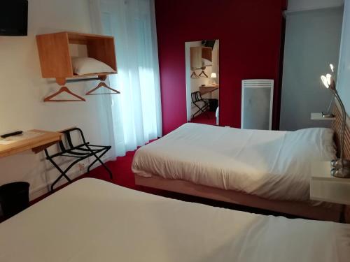 a bedroom with two beds and a red wall at Hôtel Chez Pierre d'Agos in Agos-Vidalos