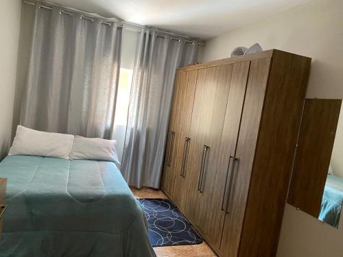 1 dormitorio con 1 cama y armario de madera en Casa com vista para o por do sol en São Thomé das Letras
