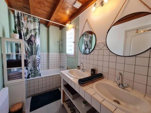 een badkamer met 2 wastafels, een bad en een spiegel bij appart cosy avec son exterieur chaleureux,piscine et parking prive in Fontvieille