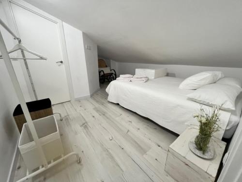 a white bedroom with a bed and a chair at Villa Trap in Guadalix de la Sierra