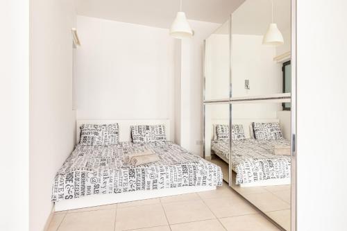 - une chambre blanche avec 2 lits et un miroir dans l'établissement Lovely studio apt in the heart of St Julians, à San Ġiljan