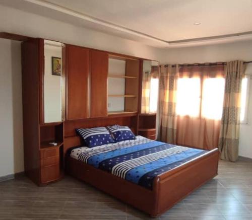 a bedroom with a large bed with a wooden headboard at RÉSIDENCE K&K - Lomé-Kégué-Kpatcha in Kopégan