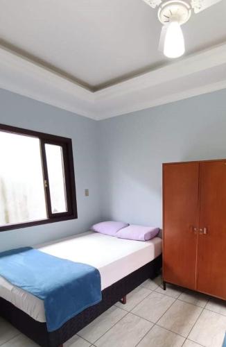 a bedroom with a bed and a cabinet and a window at iUP HOUSE Hostel in Blumenau