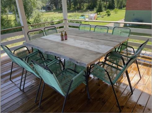 une table et des chaises en bois assises sur une terrasse couverte dans l'établissement Mitt i Sveg, Färjegatan 6, à Sveg