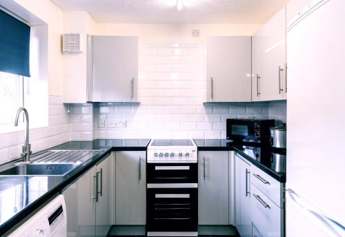 a kitchen with white cabinets and a stove top oven at Modern 2-Bed House in Stoke Gifford, NR Parkway Statn, Free Parking in Bristol