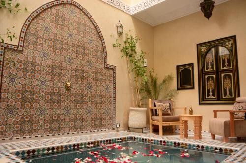 een woonkamer met een zwembad in een kamer met een muur bij Riad Bab Nour in Marrakesh