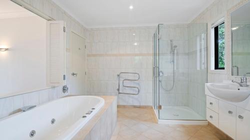 y baño con bañera, ducha y lavamanos. en Palm Gardens - Stanmore Bay Holiday Home, en Stanmore Bay