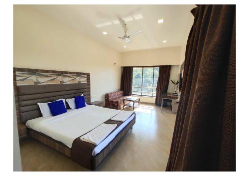 a bedroom with a large bed with blue pillows at Hotel Lalit inn in Lonavala