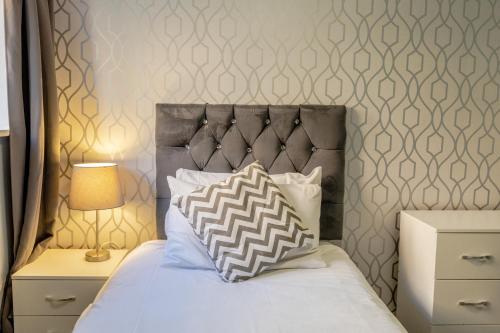 a bed with a gray headboard and a pillow on it at The Angel Hotel in Alton