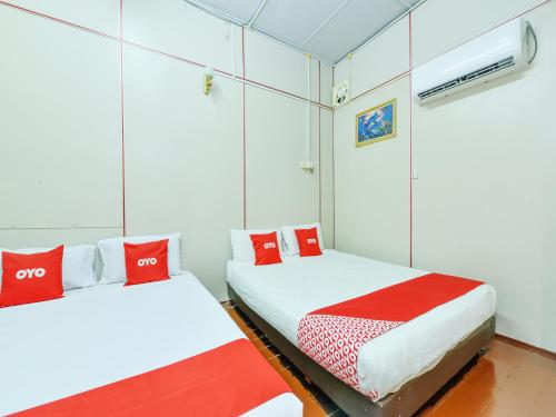 two beds in a room with red and white pillows at OYO 90627 Pulau Ketam Inn in Klang