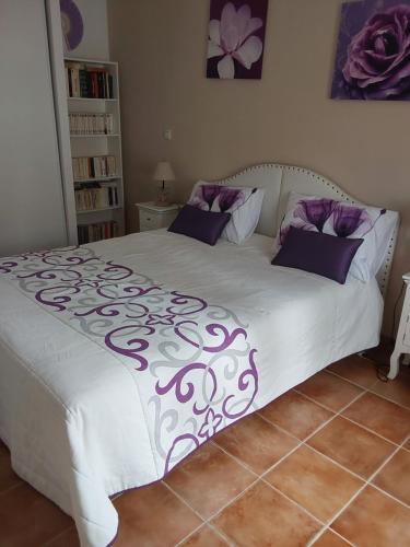 a bed with purple and white sheets and pillows at Location saisonnière en Provence in Rochefort-du-Gard