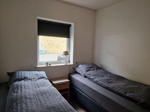 two beds in a room with a window at New flat with hot tub - No1 in Oyndarfjørður