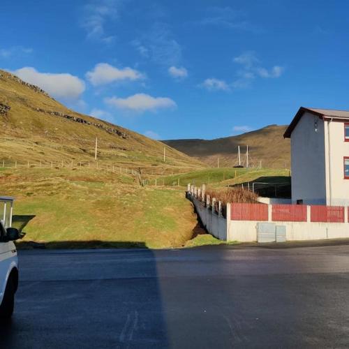 a car parked on the side of a road next to a fence at New flat with hot tub - No1 in Oyndarfjørður