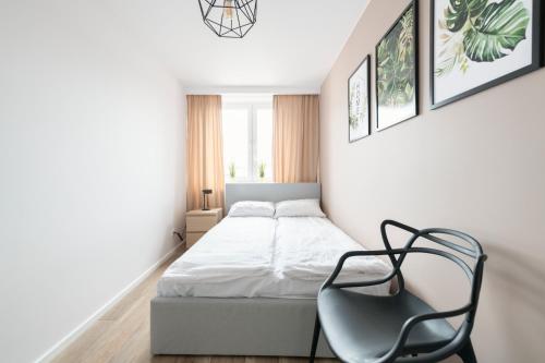 um pequeno quarto com uma cama e uma cadeira em Prime Apartments - Oliva View em Gdansk