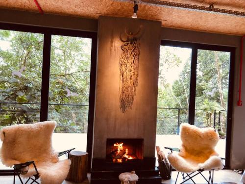 sala de estar con 2 sillas y chimenea en Casa Maikäfer, en Rodeio