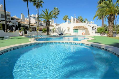 een zwembad voor een huis met palmbomen bij Beautiful 2 Bedroom Bungalow with Communal Pools in Villamartin
