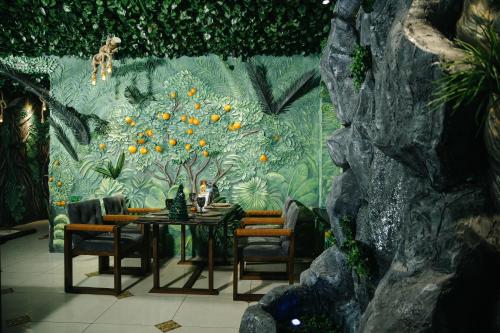 a dining room table with chairs and a wall with a mural at Asmald Palace Hotel in Kokand