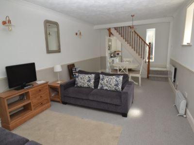ein Wohnzimmer mit einem Sofa und einem TV in der Unterkunft Quince Cottage in Ventnor
