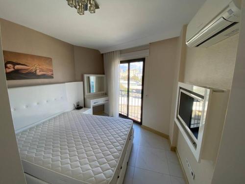 a bedroom with a bed and a television in it at Granada City’de modern lüx 1+1 in Alanya