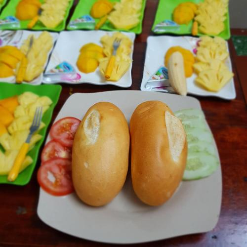 a plate with two buns and tomatoes on a table at Sun Hà Giang Hotel-tours-motorbike rental in Ha Giang