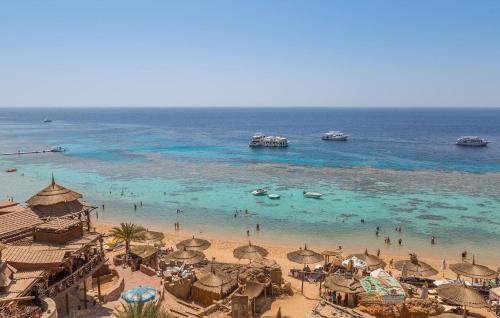 a beach with many umbrellas and people in the water at Al Crown in Sharm El Sheikh