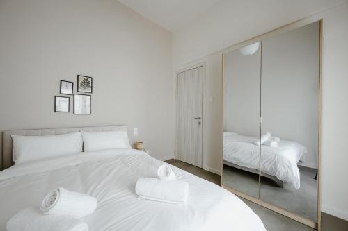 a white bedroom with a large white bed and a mirror at LB Luxury Apartments in Volos